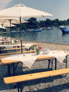 Seebar Radolfzell – Hochzeit, Tische am Seeufer mit Sonnenschirmen